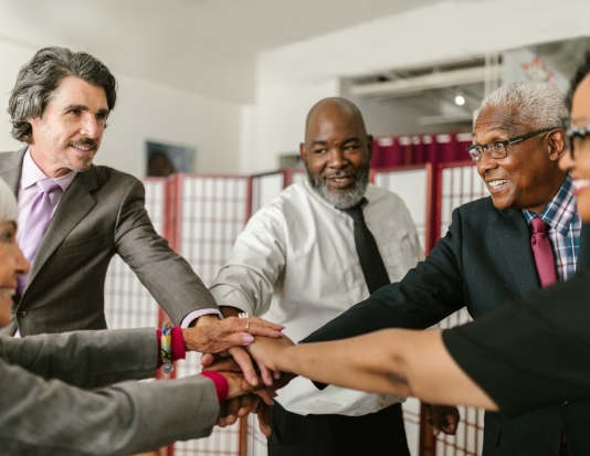 Group of adults puts their hands together